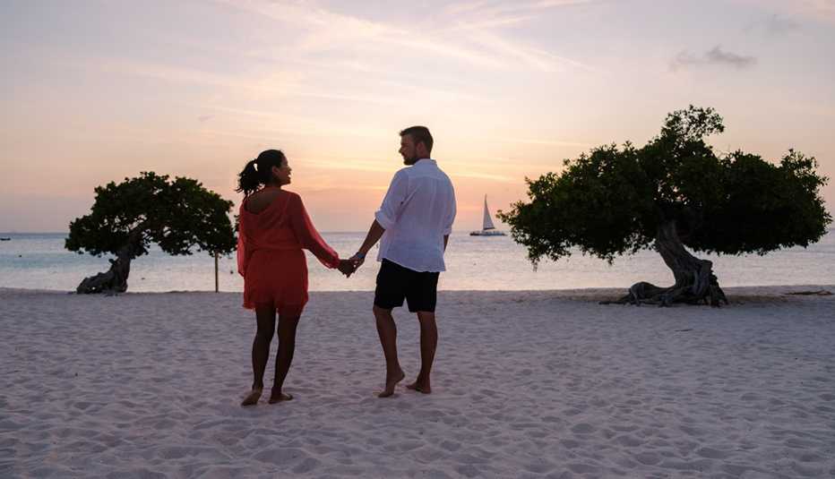 Una pareja tomados de la mano mientras estaban en la playa de Aruba. Una pareja tomados de la mano mientras estaban en la playa de Aruba.