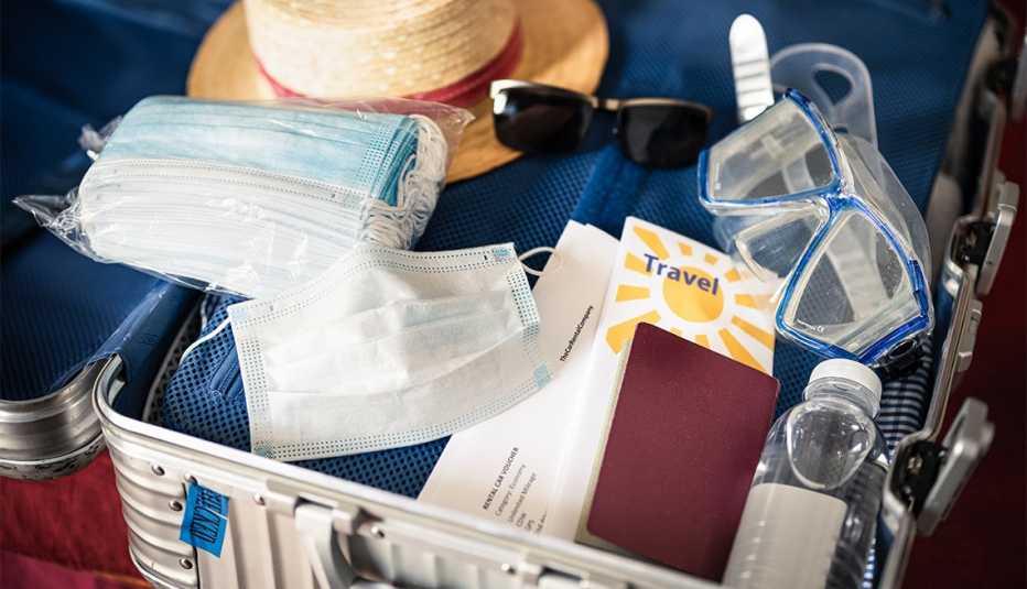 Maleta de viaje llena de desinfectante de manos, mascarillas y ropa