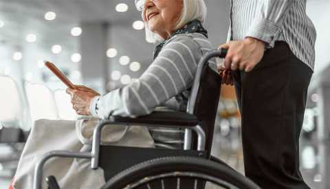 Hombre lleva a una pasajera en silla de ruedas Hombre lleva a una pasajera en silla de ruedas