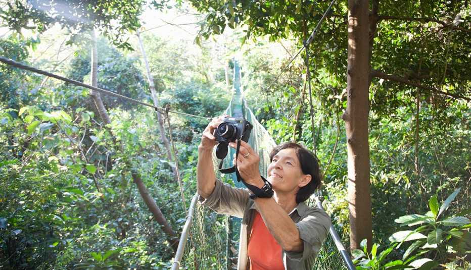 Mujer mayor en un puente colgante en un bosque tropical