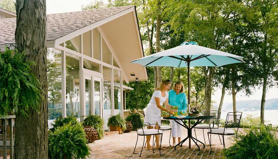 Dos mujeres vierten bebidas mientras están en el comedor de un patio exterior