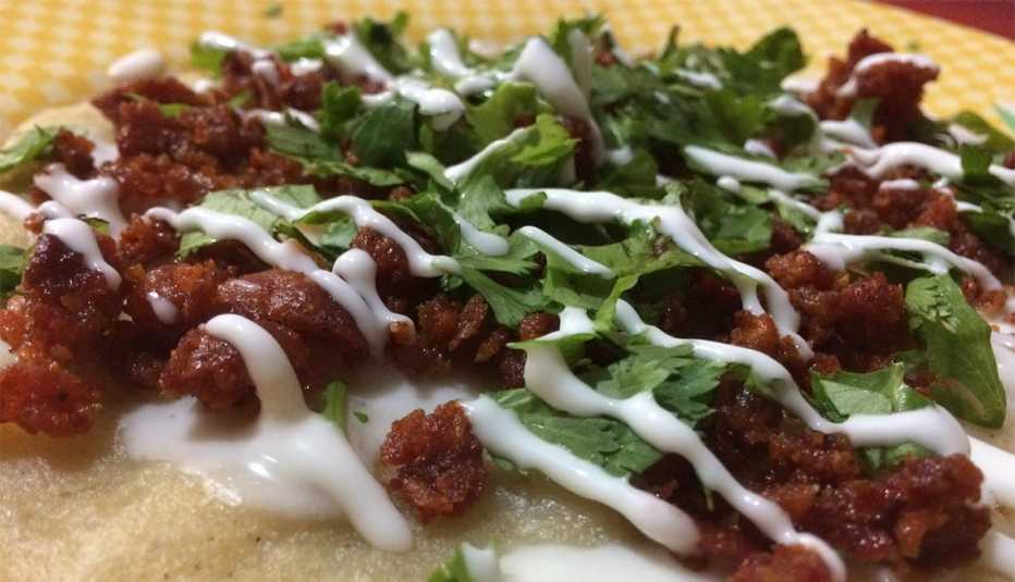 Comida mexicana conocida como huaraches, con maíz, chorizo, queso y cebolla