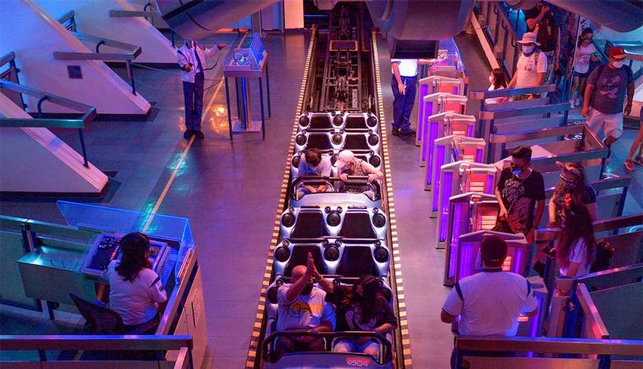 Personas mantienen distanciamiento social dentro de Space Mountain en Disneyland