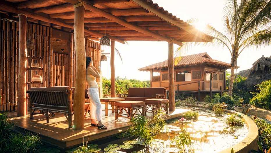 Mujer parada en el porche de un bungalow ecológico en el resort Playa Viva