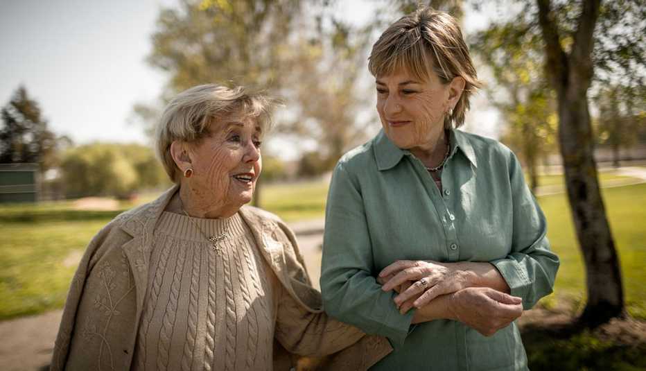 older woman and mother with locked arms walking and talking outside