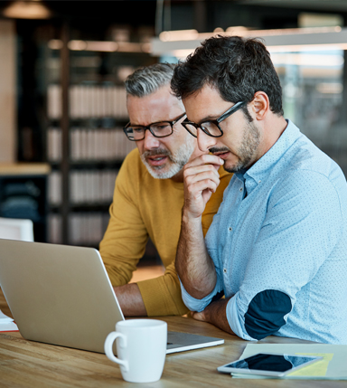 two businessmen looking at a laptop and thinking