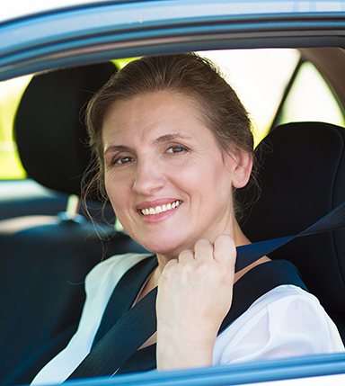 woman in drivers seat putting her seatbelt on