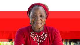 African American senior woman smiling wearing red shirt , head band, and necklace against a red background
