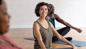 A smiling woman in a yoga class with other people