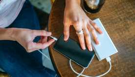 Close-up of Woman's hands plugging a mobile phone into a power bank  in a bar