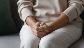 Woman with her hands on her lap and sitting on a couch