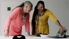 two women standing at a table looking at a laptop