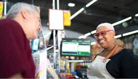 Cajera sonríe a un cliente en un supermercado Cajera sonríe a un cliente en un supermercado