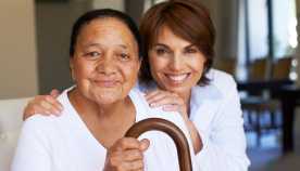 Mujer joven abraza a la mujer mayor con bastón, Caregiving Resouce Center