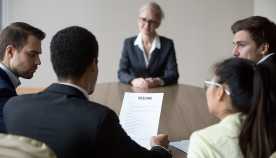 An older women at a job interview with people looking at her resume