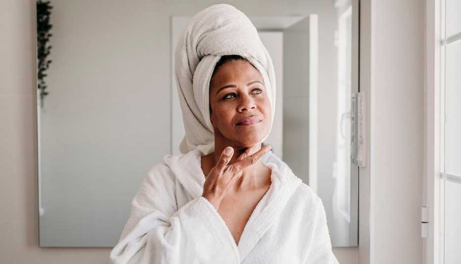 Woman applying moisturizer on face in bathroom
