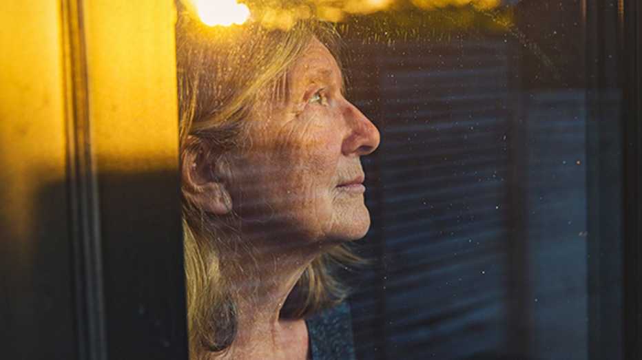 A woman looking out a window with a sad look