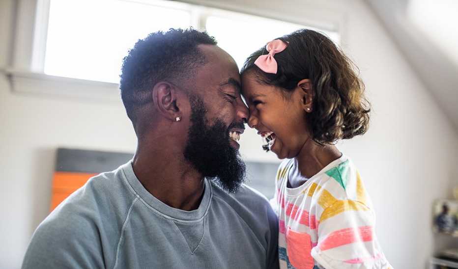 A man and a young girl laughing with their heads touching