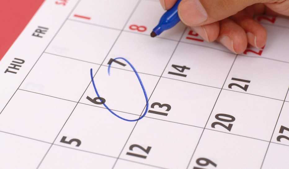 A close-up view of a hand marking a date on a calendar