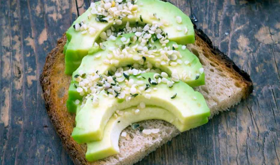 Toasted bread with avocado, cress and hemp seeds on wood
