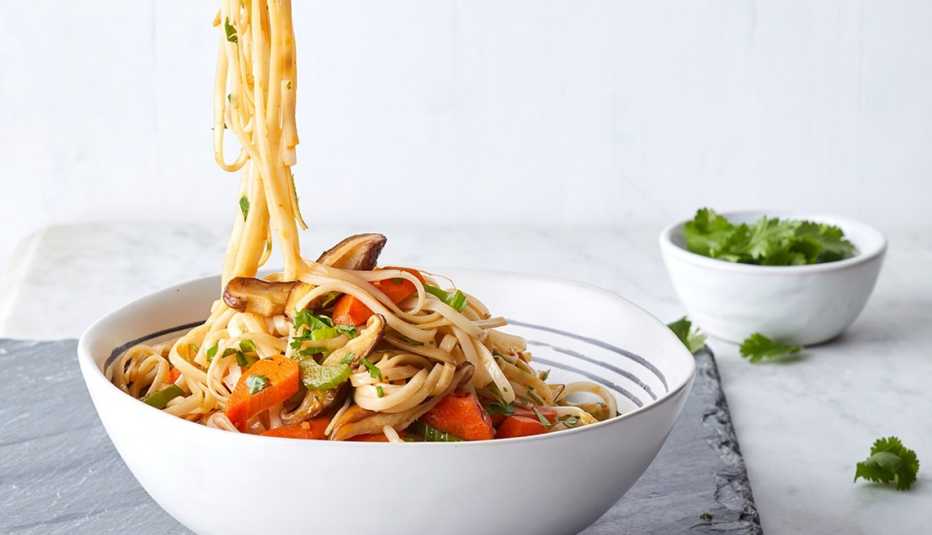 A close-up view of vegetarian lo mein with shiitakes, carrots and bean sprouts in a bowl