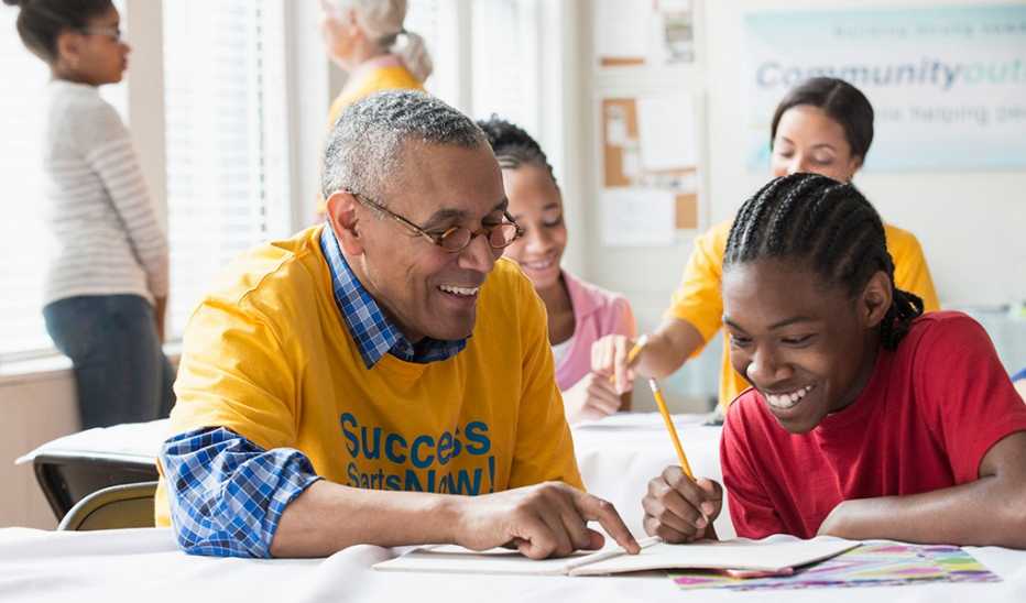 A man tutoring a student in a classroom at a school