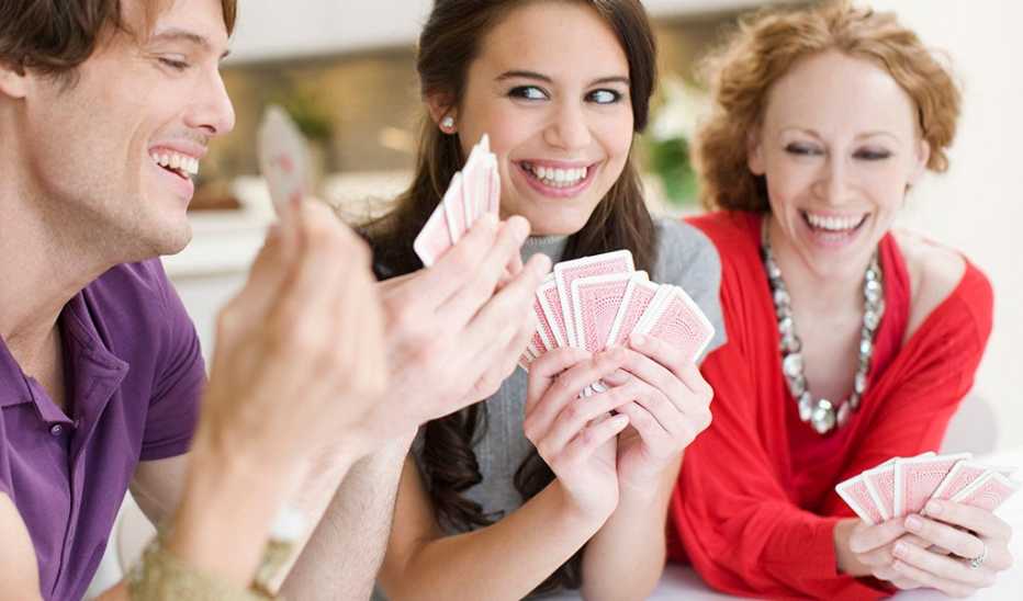 A group of people smiling and playing cards together