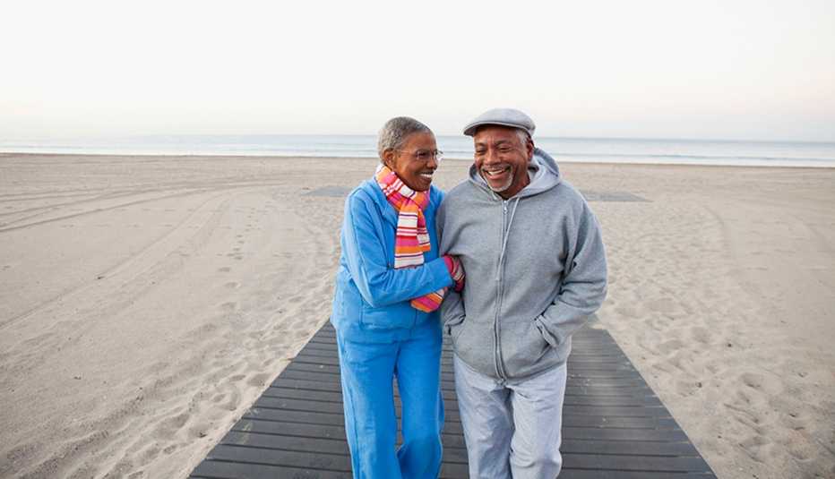 A man and woman smiling and walking together on the beach