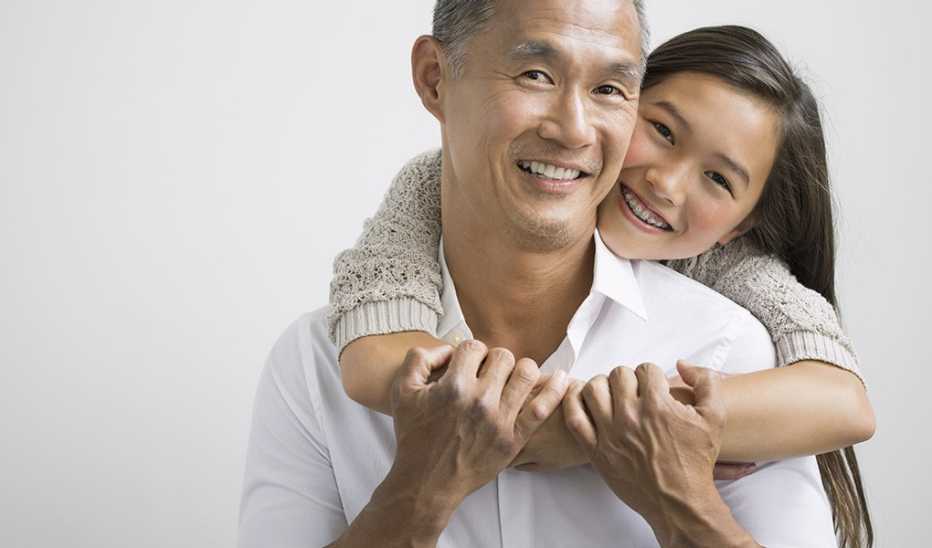 A portrait shot of a smiling father and daughter hugging
