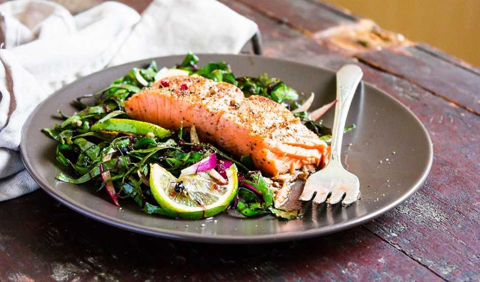 An up-close view of salmon fillet steak roasted with spices served with fresh salad