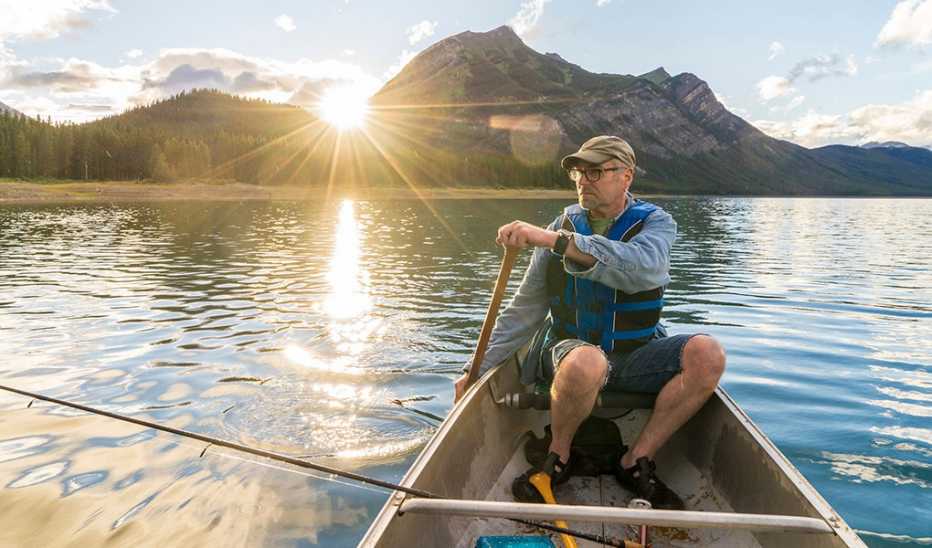 A fisherman paddling a canoe in a mountain lake