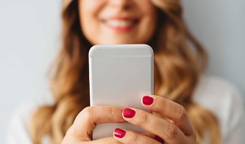A woman holding up her cell phone out in front of her