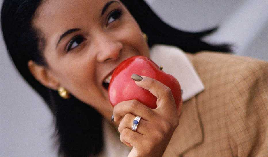 A woman taking a bite into an apple
