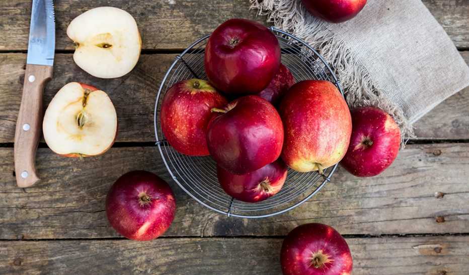 A close-up view of a bowl of apples on dark wood