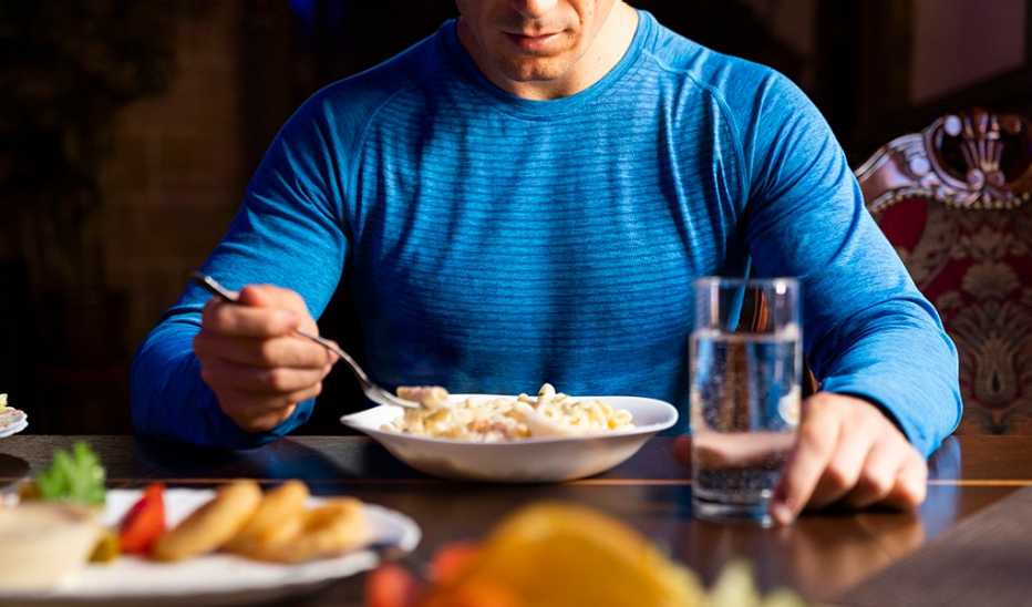 A man eating a pasta dish at a table