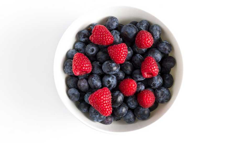 A bowl of blueberries and strawberries against a white background