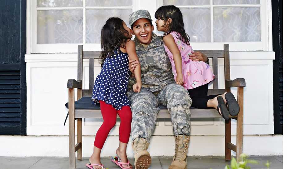 A female soldier with two young girls on a patio