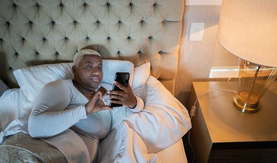 A woman using a smartphone in bed at night
