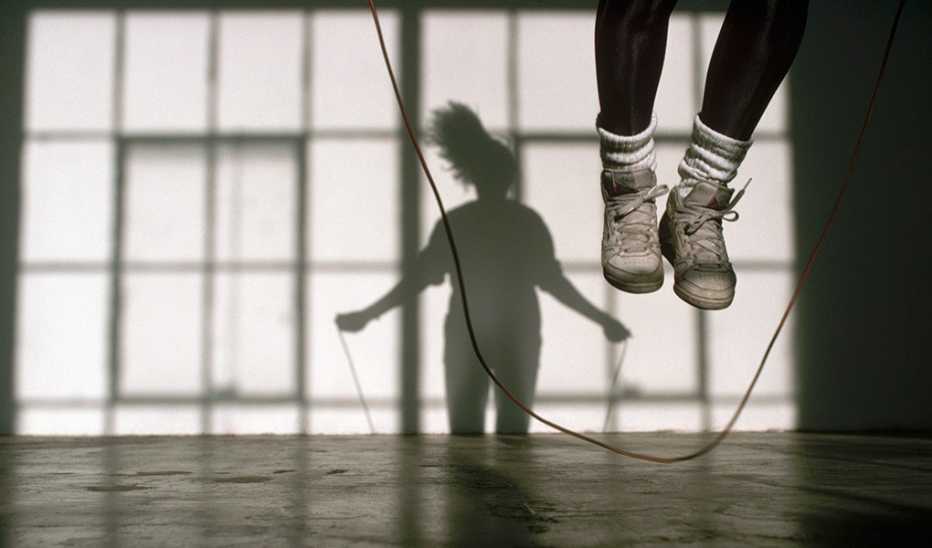 A woman jumping rope casting a shadow on the wall behind her
