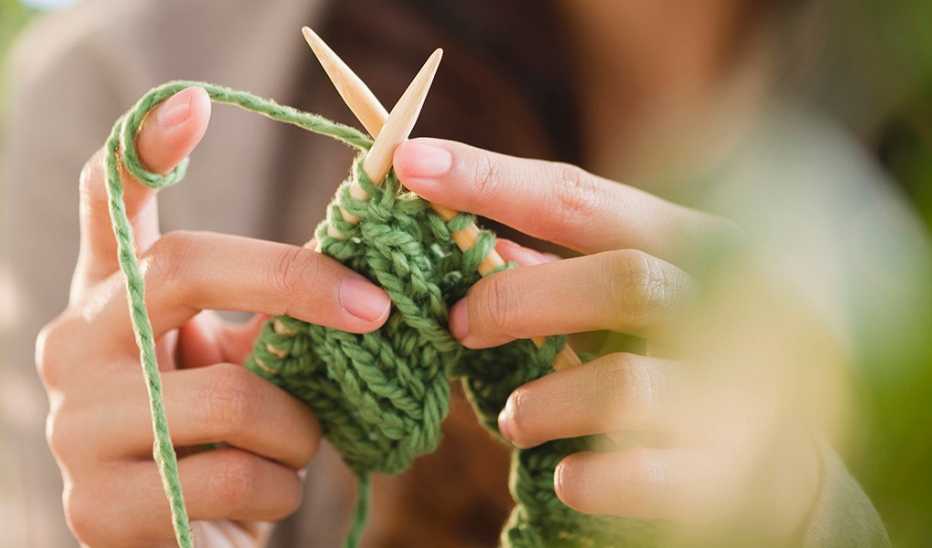 A close-up view of a person knitting with needles and yarn