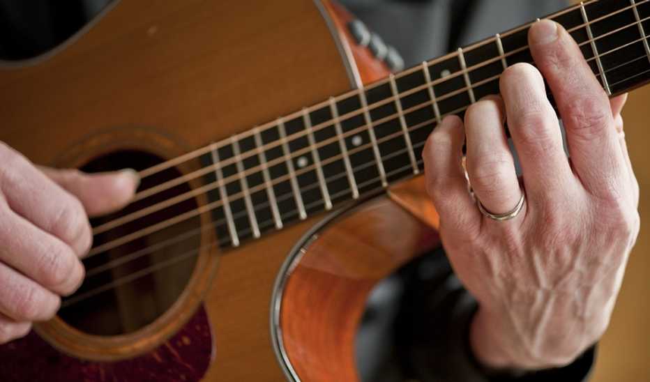 An up-close view of hands playing a guitar