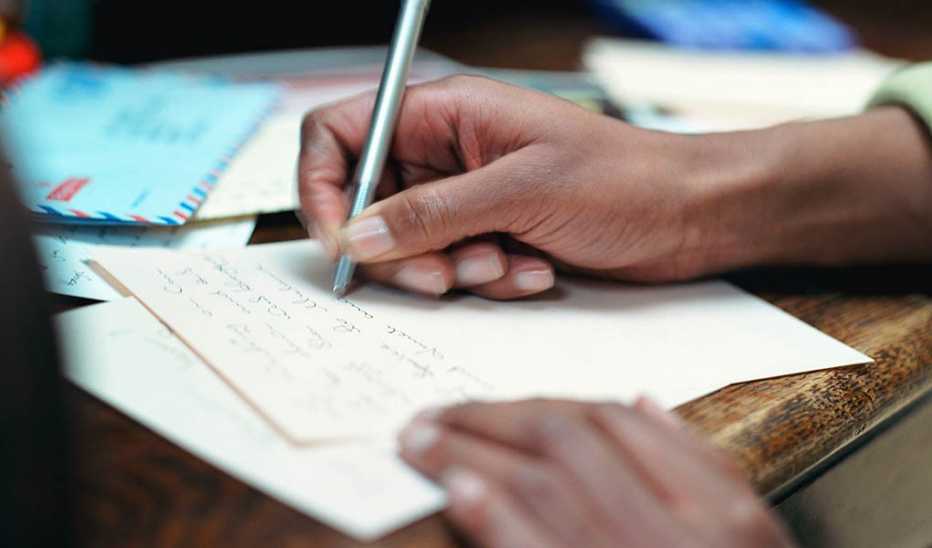 A close up of a hand as a person writes on a paper