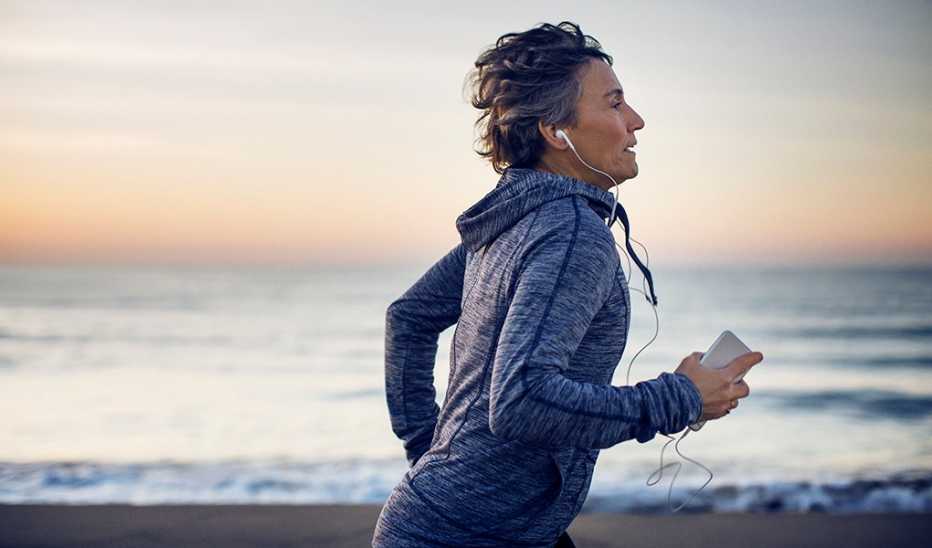 A woman running on a beach with earphones in