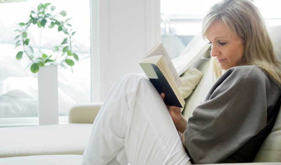 A woman reading a book on a couch
