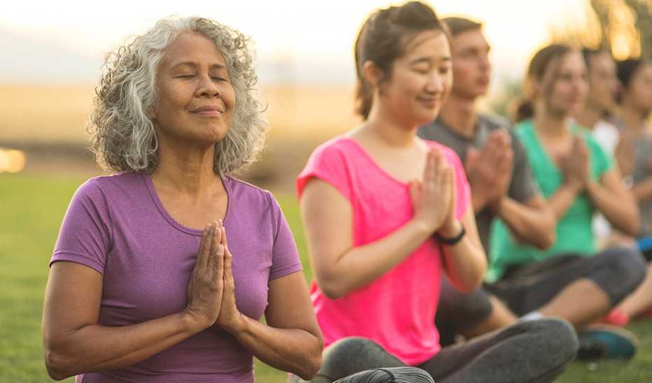 A group of people in a park meditating during a yoga class
