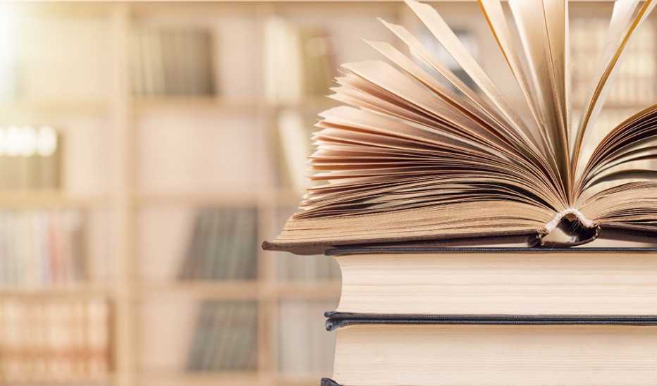 An open book stacked on top of two other books in a library