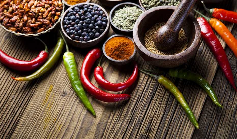 A close-up view of spices and herbs in bowls on dark wood