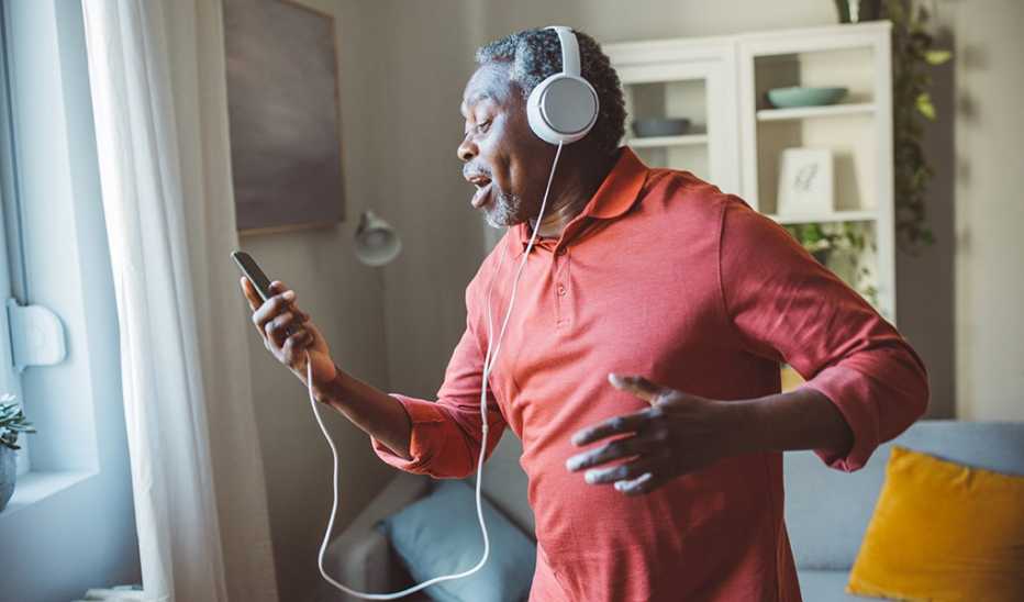 A man with headphones on his head dancing at home