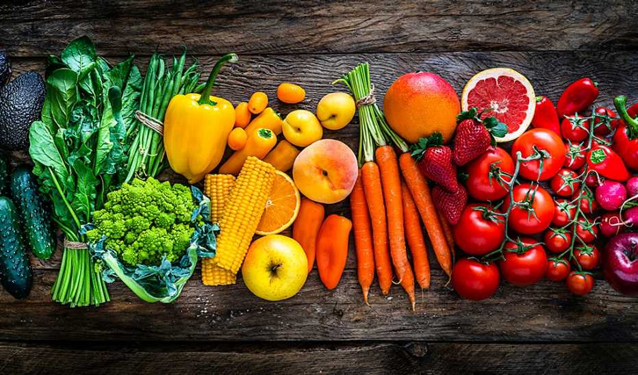 An overhead view of colorful fruits and vegetables on a wooden table