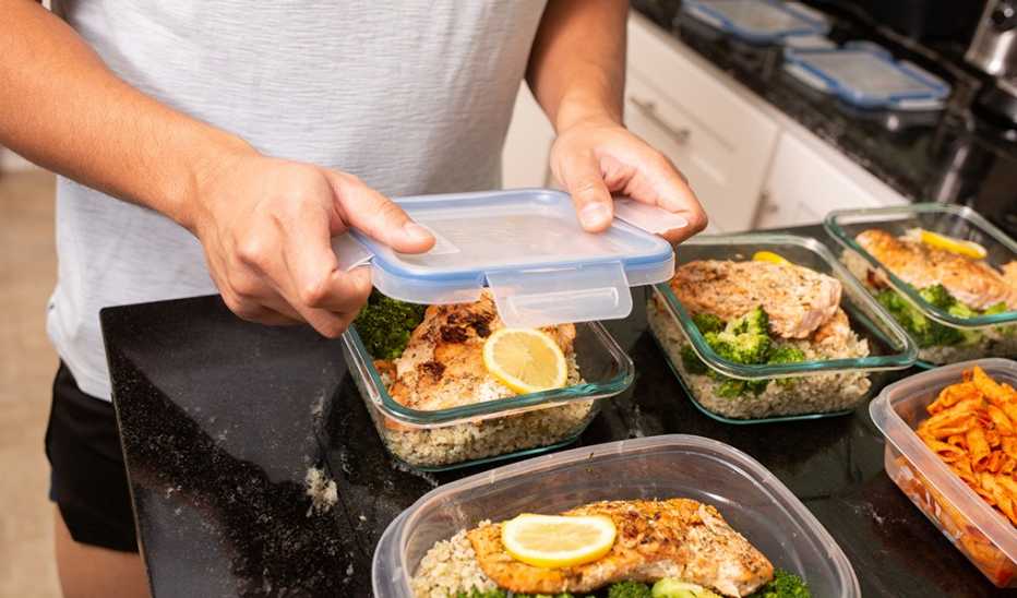 A man putting away a salmon meal prep meal into containers